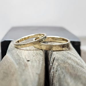 Puede incluir: Dos anillos de oro con un acabado texturizado y martillado. Los anillos son bandas circulares con un brillo amarillo met&aacute;lico y un patr&oacute;n de superficie rugoso e irregular. Las bandas est&aacute;n colocadas juntas, mostrando un dise&ntilde;o consistente.