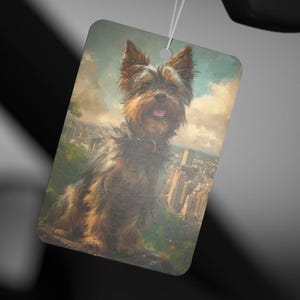 May include: A brown and black Yorkshire Terrier dog sitting on a rock with a city skyline in the background. The dog is looking at the camera and has a happy expression on its face.