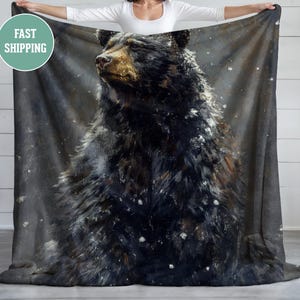 May include: A black bear with brown fur is depicted in a watercolor style against a dark gray background with white speckles. The bear is looking to the left of the image.