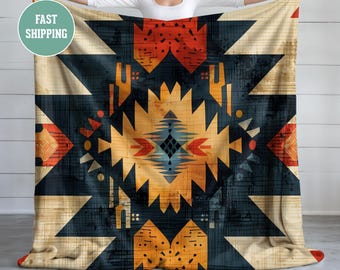 May include: A geometric patterned throw blanket with a dark blue, orange, red, and white colour scheme. The blanket has a tribal design with a central diamond shape.