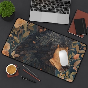 May include: A black bear with a detailed, textured design is surrounded by a floral pattern on a dark blue background. The bear's face is visible, and the design includes leaves, flowers, and vines.