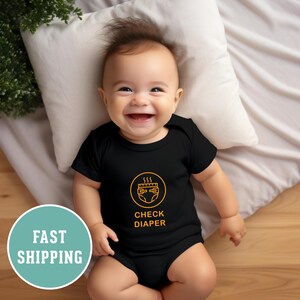May include: A black baby onesie with a yellow graphic of a nappy with steam coming off of it. The text "CHECK DIAPER" is below the graphic.