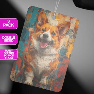 May include: A colorful car air freshener featuring a painting of a smiling corgi dog. The background is a mix of abstract shapes in shades of blue, yellow, red, and orange.