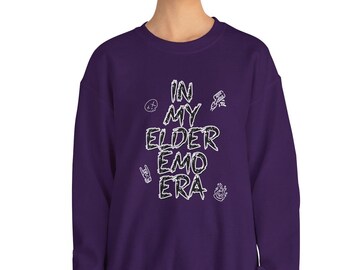 May include: Purple sweatshirt with the text "In My Elder Emo Era" in white lettering. The text is surrounded by small graphic designs.