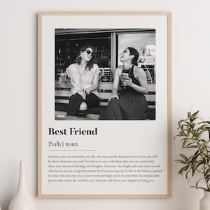 May include: Black and white photo of two friends laughing together in front of a store. The photo is framed and has a definition of the word "Best Friend" below it.