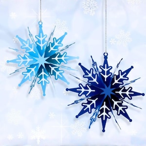 以下が含まれることがあります： 青色の2つの吊り下げ式雪の結晶オーナメント。 雪の結晶は複雑な切り抜きデザインで、銀色の紐で吊り下げられています。 背景は、追加の雪の結晶アクセントが付いた、柔らかくぼやけた青色です。
