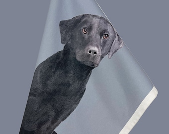 May include: A black Labrador Retriever dog is printed on a white tea towel with a grey background. The towel is hanging from a hook.