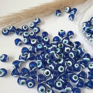 Könnte beinhalten: Ein großer Haufen blauer und weißer Glücksbringer-Perlen. Die Perlen sind rund und haben ein Loch in der Mitte zum Aufziehen. Sie sind ein beliebter Glücksbringer für Schutz und Glück.
