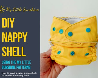 Könnte beinhalten: Eine hellgelbe DIY-Windel mit türkisfarbenen Druckknöpfen, gehalten in einer Hand. Der Text links lautet "DIY NAPPY SHELL" und "USING THE MY LITTLE SUNSHINE PATTERNS". Die Windel ist aus weichem, saugfähigem Material.