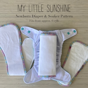 Puede incluir: Un patrón de pañal y absorbente para recién nacidos de color blanco con ribete colorido. El pañal está colocado plano con el absorbente en la parte superior. El texto "My Little Sunshine Newborn Diaper & Soaker Pattern Fits from approx. 6-17lb" está impreso encima del pañal.