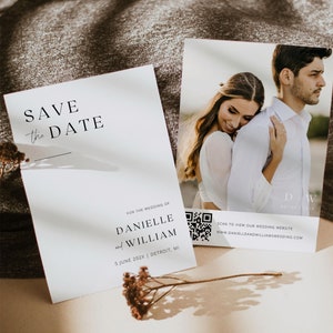 Peut inclure: Carte de sauvegarde de la date avec un design minimaliste mettant en scène une photo en noir et blanc d'un couple qui s'embrasse. La carte comprend les noms du couple, la date du mariage et le lieu, ainsi qu'un code QR pour accéder à leur site web de mariage.