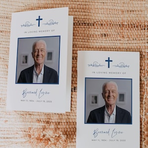 May include: Two white funeral program cards featuring a blue cross, decorative swirls, and the text IN LOVING MEMORY OF. Each card displays a photograph of a man, the name Bernard Levine, and the dates MAY 11, 1934 - JULY 19, 2020.