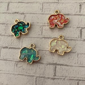 May include: Four gold-tone elephant charms with iridescent glitter inside. The elephants are in red, blue, green, and white.