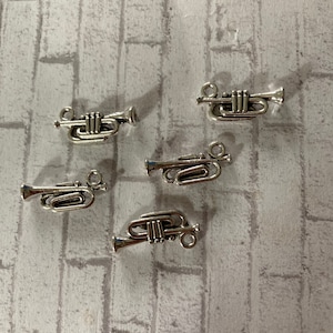May include: Five silver trumpet charms with a loop for attaching to a necklace or bracelet.