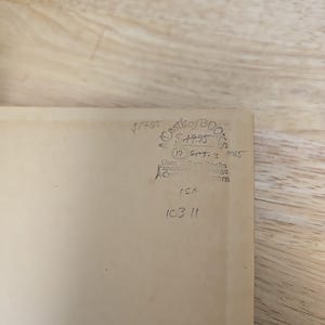 K&ouml;nnte beinhalten: Ein beigefarbener Buchumschlag mit handschriftlichem Text und Markierungen. Der Text enth&auml;lt den Preis, den Namen "Castle of Books" und das Datum "19 Sep 3 1005". Zus&auml;tzliche handschriftliche Zahlen und Buchstaben sind ebenfalls sichtbar.