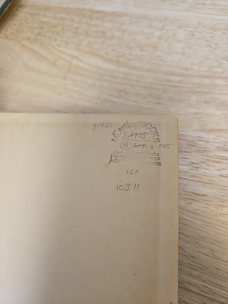 K&ouml;nnte beinhalten: Ein beigefarbener Buchumschlag mit handschriftlichem Text und Markierungen. Der Text enth&auml;lt den Preis, den Namen "Castle of Books" und das Datum "19 Sep 3 1005". Zus&auml;tzliche handschriftliche Zahlen und Buchstaben sind ebenfalls sichtbar.