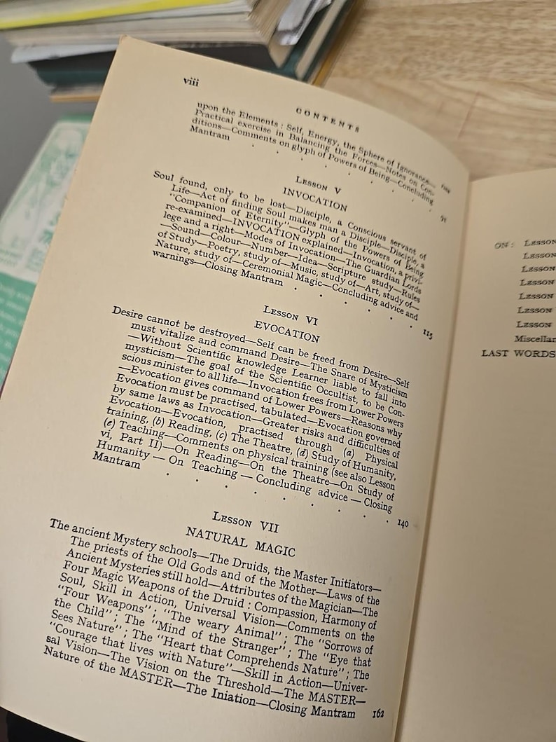 K&ouml;nnte beinhalten: Aufgeschlagenes Buch mit Texten &uuml;ber Beschw&ouml;rung, Evokation und Naturmagie. Die Seiten sind vergilbt, und der Text enth&auml;lt &Uuml;berschriften wie 'Lektion V' und 'Lektion VI' mit detaillierten Erkl&auml;rungen und Unterpunkten.