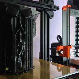 K&ouml;nnte beinhalten: Ein schwarzes 3D-gedrucktes Objekt mit filigranen Details wird auf einem Prusa 3D-Drucker gedruckt. Das Objekt befindet sich auf einer Plattform und der Drucker ist in Betrieb.