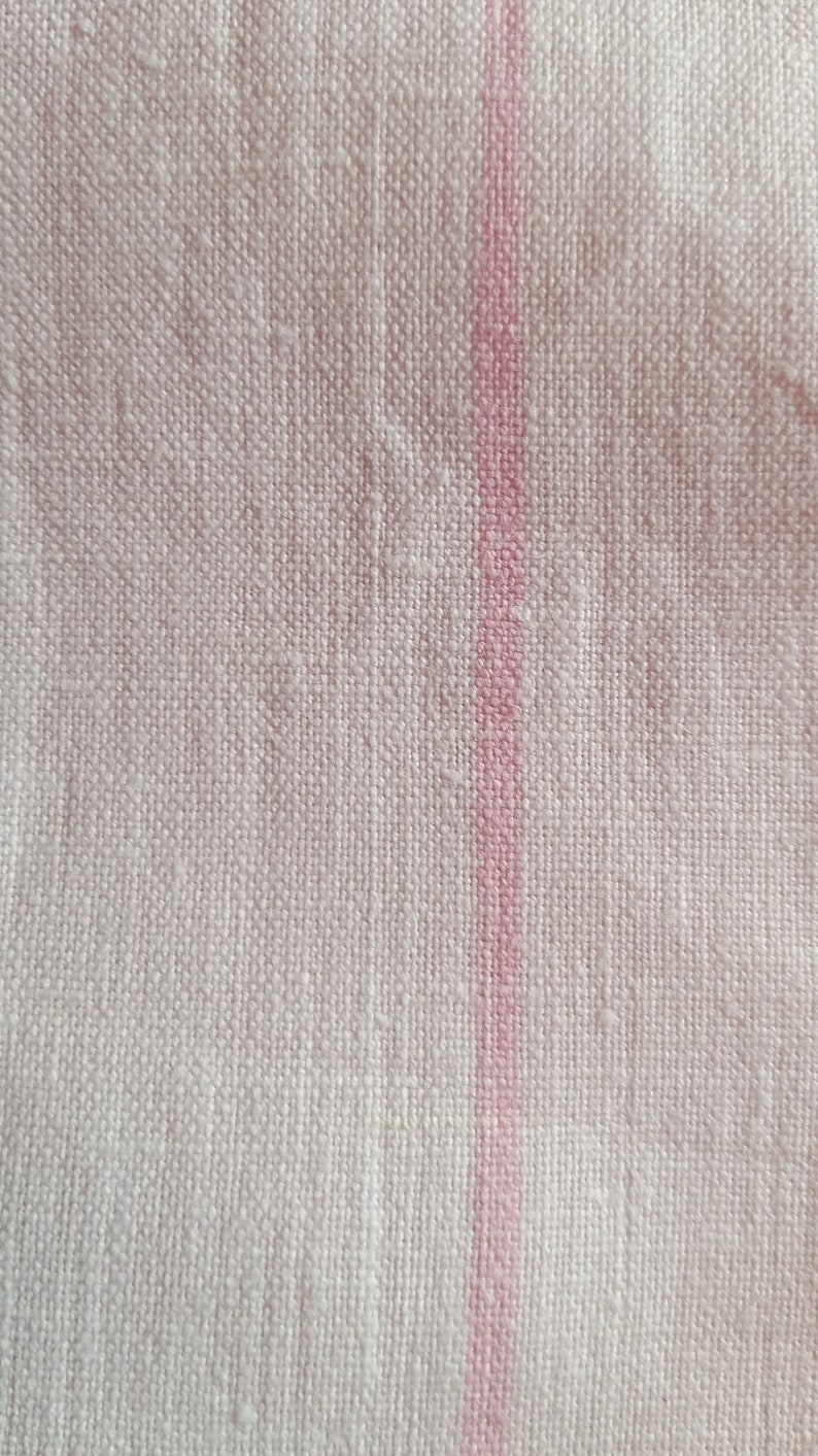 May include: White fabric with a single pink stripe running vertically down the centre.
