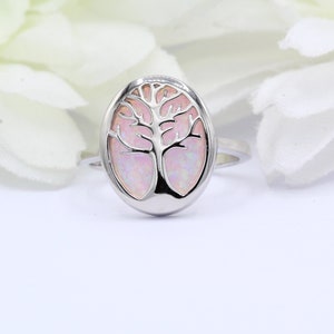 May include: A silver ring with a pink opal tree of life design.