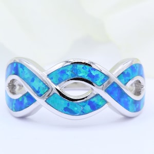 May include: A silver ring with a blue opal design. The ring is in the shape of an infinity symbol.