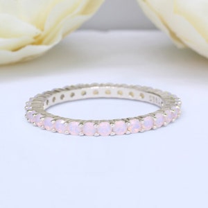 May include: A delicate silver band ring with a row of small, pale pink opal stones.