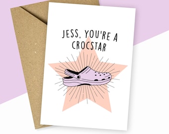 Könnte beinhalten: Eine weiße Karte mit einem rosa Stern und einer lila und schwarzen Cartoon-Illustration eines Croc-Schuhs. Der Text auf der Karte lautet "Jess, you're a Crocstar".