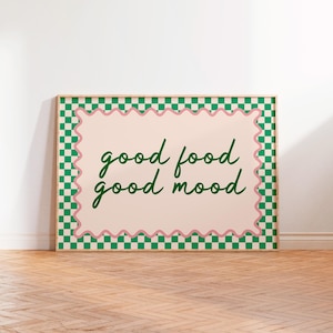 Könnte beinhalten: Ein gerahmter Kunstdruck mit den Worten "good food good mood" in grüner Schrift. Der Druck hat einen hellrosa Hintergrund mit einem wellenförmigen rosa Rand. Der Rahmen ist von einem grün-weißen Karomuster umgeben.