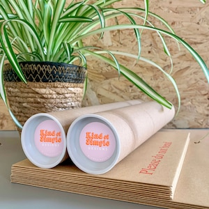 May include: Two brown cardboard tubes with white end caps. Each end cap has a pink circle with the text "Kind of Simple Designs" in orange.