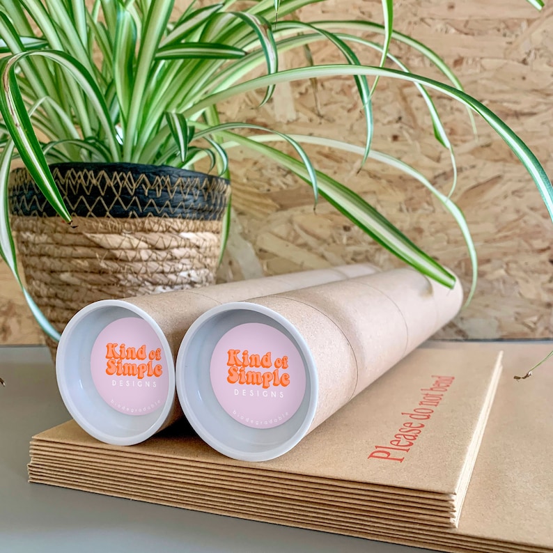 May include: Two brown cardboard tubes with white end caps. Each end cap has a pink circle with the text "Kind of Simple Designs" in orange.
