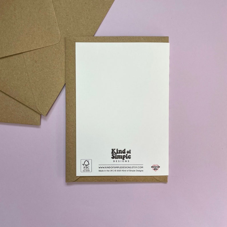 May include: The back of a white card with brown paper envelope. The card has the text "Kind of Simple Designs" and a website address. The card also has a small FSC logo and a small heart with the text "recycle me".
