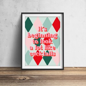 May include: A framed print with a green, red, and pink diamond pattern background. The text "it's beginning to look a lot like cocktails" is written in pink and red letters.