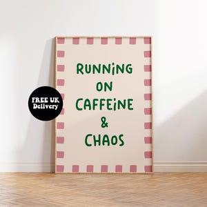 May include: A framed poster with the words "RUNNING ON CAFFEINE & CHAOS" in green. The poster has a light pink background with a pink square border. A black circle with white text that says "FREE UK Delivery" is on the left.