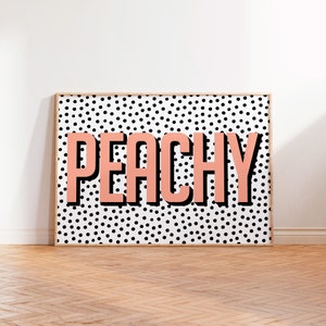 May include: Peachy in pink lettering on a black and white polka dot background. The print is framed in a light wood frame.