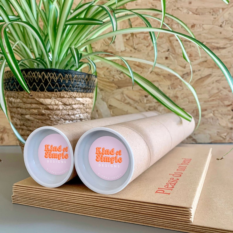 May include: Two brown cardboard tubes with white end caps. Each end cap has a pink circle with the text "Kind of Simple Designs" in orange.