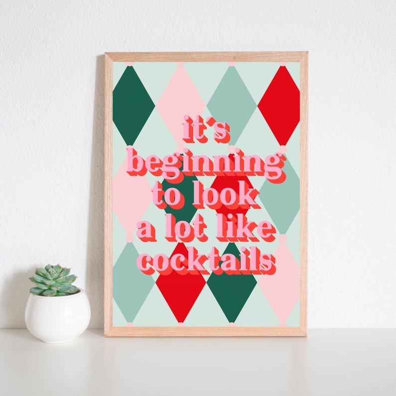 May include: A framed print with a green, red, and pink diamond pattern. The text "it's beginning to look a lot like cocktails" is written in pink letters.