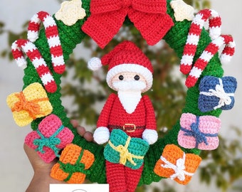 May include: A crocheted Christmas wreath with a Santa Claus figure holding a gift. The wreath is decorated with red and white candy canes, a red bow, and various colorful crocheted gifts.