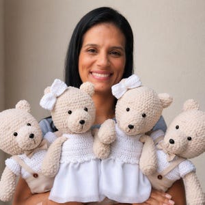Pode incluir: Quatro ursos de pelúcia feitos de crochê. Dois ursos usam vestidos brancos de crochê com laços brancos na cabeça. Dois ursos usam camisas brancas de crochê com calças de suspensório bege e pequenas gravatas borboleta. Fio bege e olhos pretos.