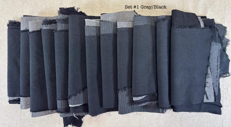 May include: A collection of gray and black fabric scraps, arranged in a vertical stack. The fabrics vary in texture and pattern, including stripes and solid colors. The text "Set #1 Gray/Black" is visible.