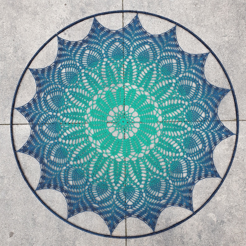 Puede incluir: Un gran encaje de ganchillo redondo con un dise&ntilde;o degradado en azul turquesa y azul. El encaje est&aacute; hecho con un punto delicado y de encaje y tiene una forma circular.