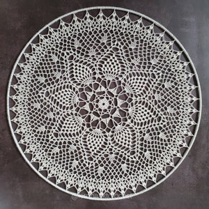 Puede incluir: Un gran encaje de ganchillo blanco con un dise&ntilde;o circular. El encaje est&aacute; hecho con un patr&oacute;n delicado e intrincado y tiene una forma circular.
