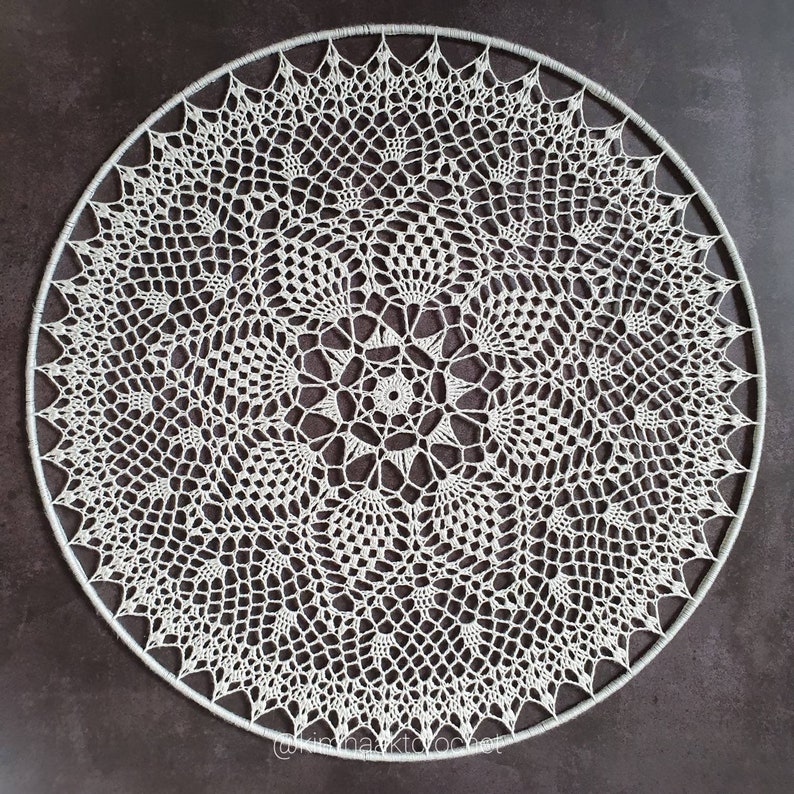 Puede incluir: Un gran encaje de ganchillo blanco con un dise&ntilde;o circular. El encaje est&aacute; hecho con un patr&oacute;n delicado e intrincado y tiene una forma circular.