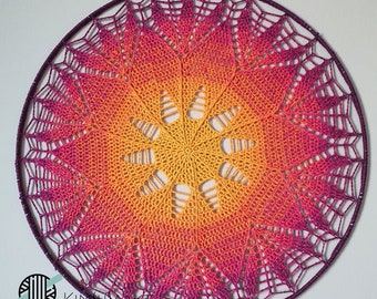 May include: A large, circular crochet mandala with a gradient of pink, orange, and yellow. The mandala is made with a fine yarn and has a delicate, intricate design.