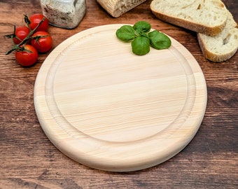 May include: A round wooden cutting board with a raised edge, a small glass jar with a cork lid, a few red tomatoes, and a sprig of green basil leaves on a brown wooden surface.