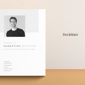Op de afbeelding: Een zwart-witfoto van een persoon met een neutrale uitdrukking. De tekst "Bewerbung als MARKETING MANAGER bei der Bucherei Deutschland GmbH" staat onder de foto. De tekst "Felix Winkler" staat bovenaan de pagina. De tekst "Deckblatt" staat in de rechterbovenhoek van de pagina.