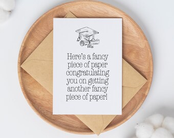 Puede incluir: Una tarjeta blanca con texto negro y un dibujo simple de un gorro de graduación y un diploma. El texto dice "Here's a fancy piece of paper congratulating you on getting another fancy piece of paper!"