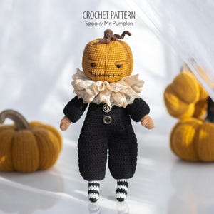 May include: A handmade crochet doll with a pumpkin head, wearing a black outfit with a ruffled collar and striped socks. The doll has a stitched face and is accompanied by two crochet pumpkins. The text "CROCHET PATTERN Spooky Mr. Pumpkin" is visible.