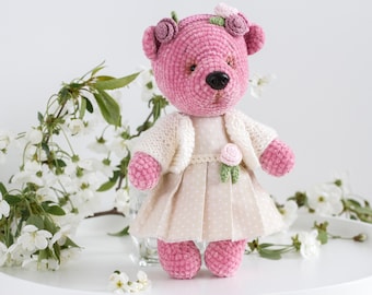 Oso de peluche rosa tejido a crochet con vestido de algodón y suéter blanco con corona de flores.