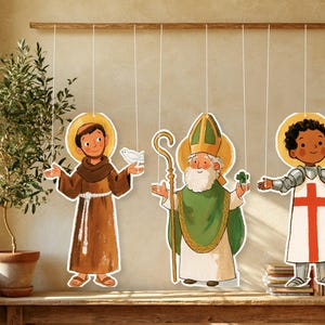 May include: Three hanging paper cutouts featuring illustrated figures: a brown-robed monk with a white dove, a bishop in green vestments holding a gold staff and shamrock, and a knight in silver armor holding a sword with a red cross emblem.