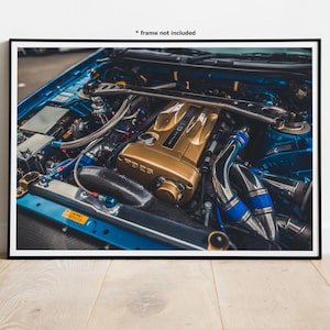 May include: A close-up of a blue car engine with a gold engine block. The engine has blue and silver pipes and hoses.